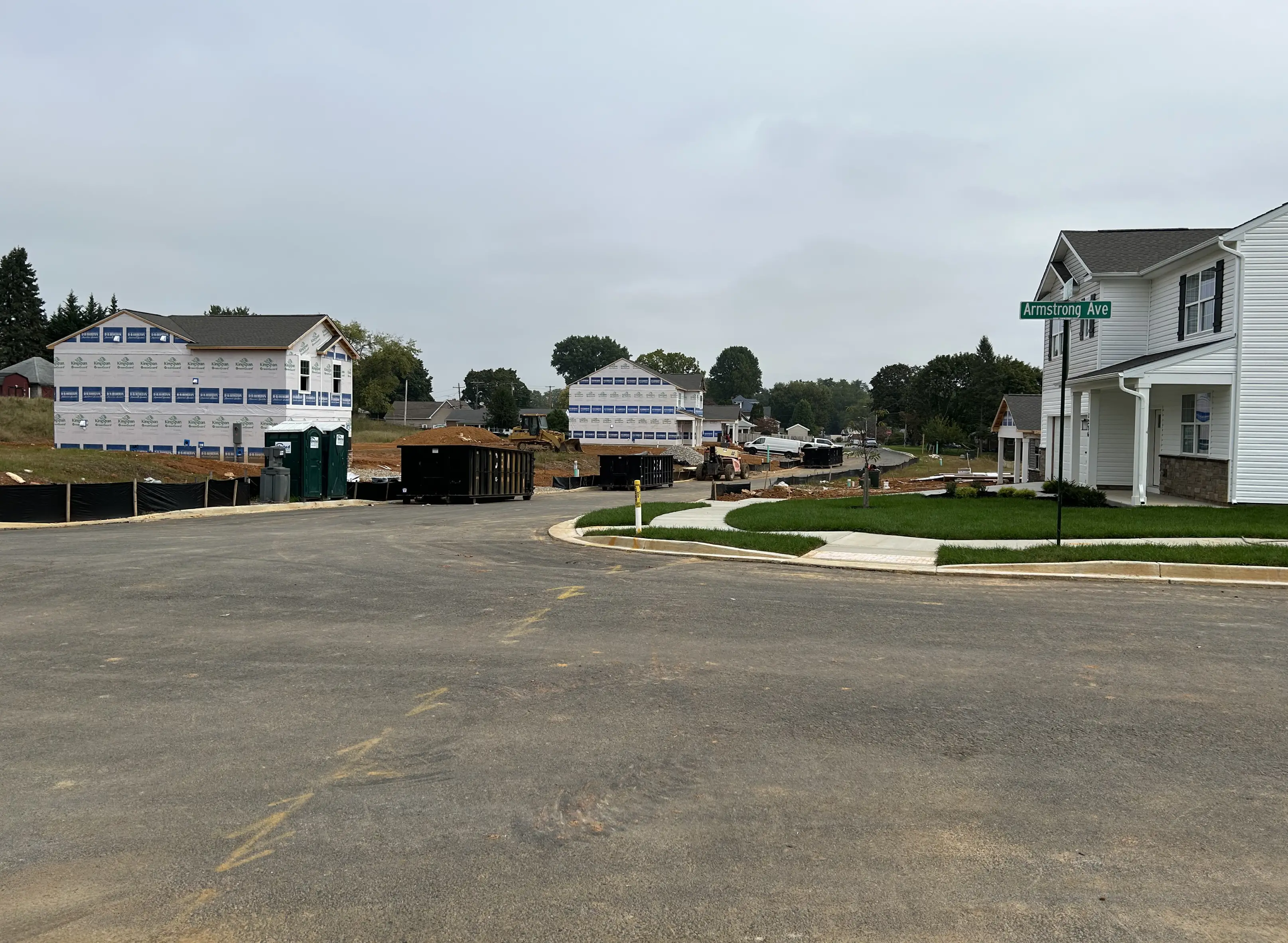 A residential street with houses and a truck blocking the road.